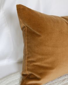 a brown pillow sitting on top of a white bed