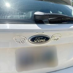 the front end of a white ford vehicle with an emblem on it's hood