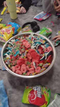 a bowl full of cereal sitting on top of a table next to bags of candy