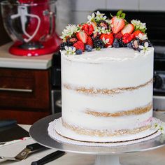 a white cake with berries and flowers on top