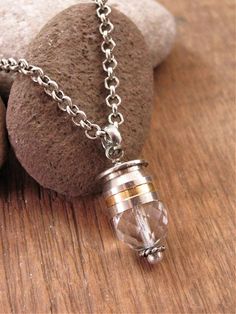 a necklace with a small glass bead hanging from it's side on a rock