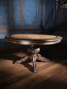 a round wooden table sitting on top of a hard wood floor next to a blue wall