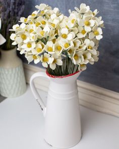 a white pitcher filled with lots of white flowers