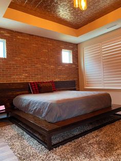 a bed sitting in the middle of a bedroom next to a window with shutters