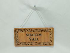 a wooden sign that says shaloh y'all hanging on a white wall with chains