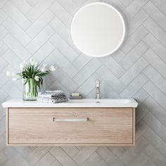 a bathroom sink with a mirror above it next to a rug and potted plant