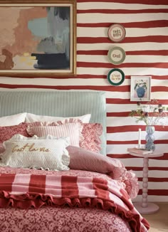 a bed with red and white striped wallpaper in a small room next to a painting on the wall