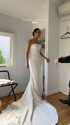 a man kneeling down next to a woman in a white wedding dress on a wooden floor