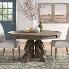 a dining room table with four chairs and a vase on the table in front of it