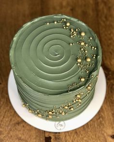 a green cake with gold sprinkles sitting on top of a white plate