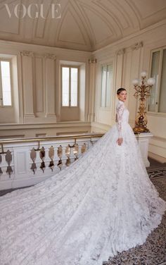 a woman in a white wedding dress standing on a balcony with an ornate chandelier