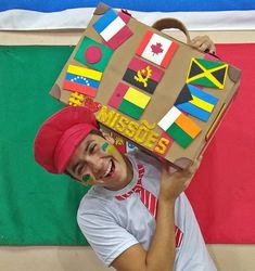 a man holding up a cardboard box with flags on it's face and smiling at the camera