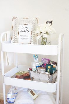 a white shelf with some items on top of it and a sign that says stay awhile