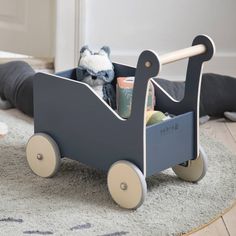 a blue toy wagon filled with toys on top of a rug