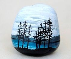 a painted rock sitting on top of a white table covered in blue and black trees