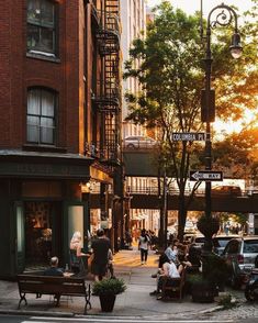 people are sitting on benches in the middle of an urban area with tall buildings and trees