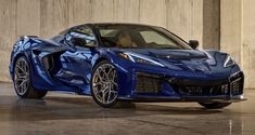 a blue sports car is parked in an empty room with concrete walls and flooring