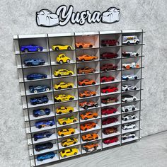 a display case filled with lots of different types of toy cars next to a wall