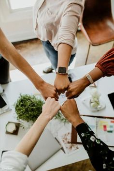 four people holding hands in the middle of a table