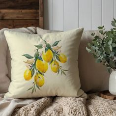 a pillow with lemons painted on it sitting on a couch next to a potted plant