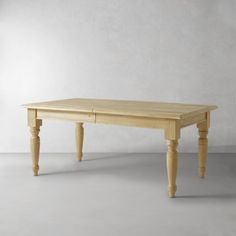 a wooden table sitting on top of a white floor next to a gray wall in an empty room