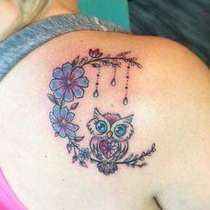 an owl and flowers tattoo on the back of a woman's left shoulder,