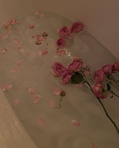 pink roses floating in a bathtub with water on the floor and petals scattered around