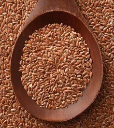 a wooden spoon filled with seeds on top of a mat