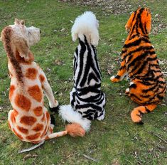 three stuffed animals sitting in the grass with their backs turned to look like zebras