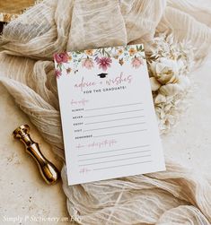 a note with flowers on it sitting next to a gold bottle and some other items