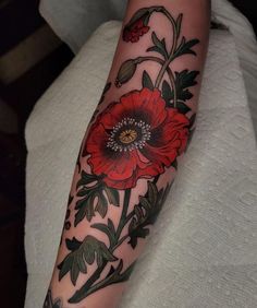 a woman's arm with a red flower tattoo on the left forearm and an insect in the center