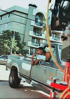 a man sitting in the back of a pick up truck talking on a cell phone