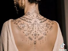 the back of a woman's neck is adorned with intricately designed tattoos and beads