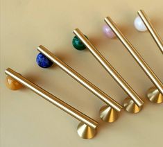 six different colored balls and metal handles on a white surface with gold, blue, pink, green, yellow or orange