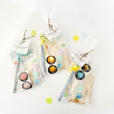 three bags filled with different types of items on top of a white table covered in confetti