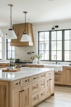 a large kitchen with wooden cabinets and white marble counter tops, along with two pendant lights hanging from the ceiling