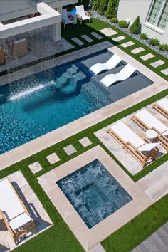 an aerial view of a swimming pool with lounge chairs around it and grass on the ground