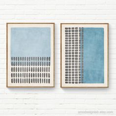 two framed art pieces on a white brick wall, one with blue and grey squares