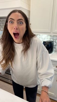 a woman standing in front of a kitchen counter with an open mouth