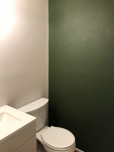 a white toilet sitting in a bathroom next to a sink and mirror on the wall