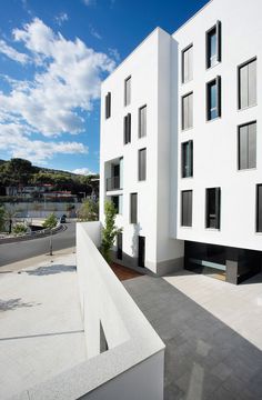 an apartment building with white walls and balconies on the outside, overlooking a parking lot