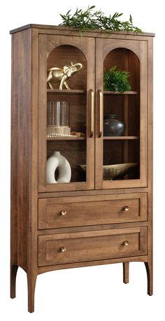 a wooden cabinet with glass doors and shelves on the front, decorated with greenery