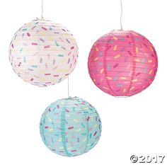 three paper lanterns with sprinkles are hanging from strings on a white background