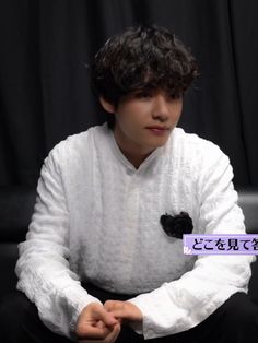 a young man sitting on top of a black chair