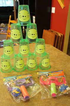 some toys are sitting on a table with plastic cups in the shape of piggies