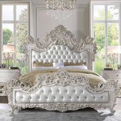 an ornate white bed in a bedroom with chandelier and two lamps on the nightstands