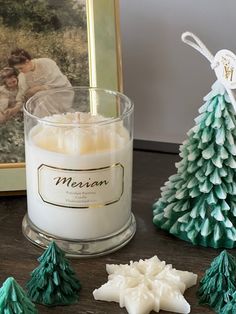 a candle sitting on top of a wooden table next to christmas trees and other decorations