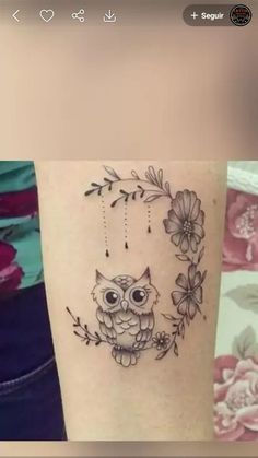 an owl tattoo on the arm with flowers around it