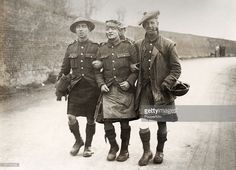 three men in uniforms are standing on the side of a road with their backs to each other