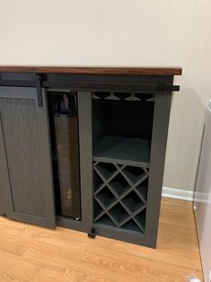 an entertainment center with wine rack and sliding doors on the front, in a room with hard wood flooring